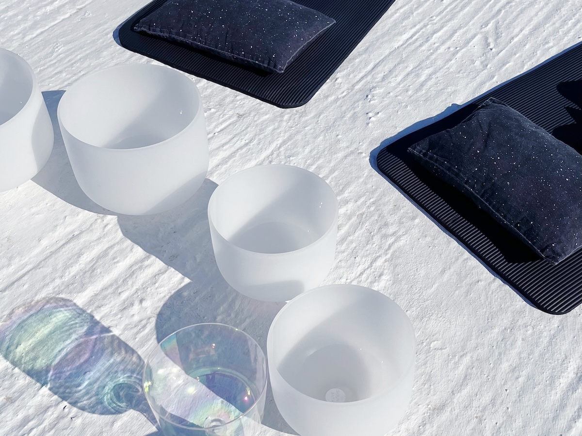 Close-up of crystal and alchemical singing bowls on a white stone terrace in Kimolos, with soft cushions on black mats.