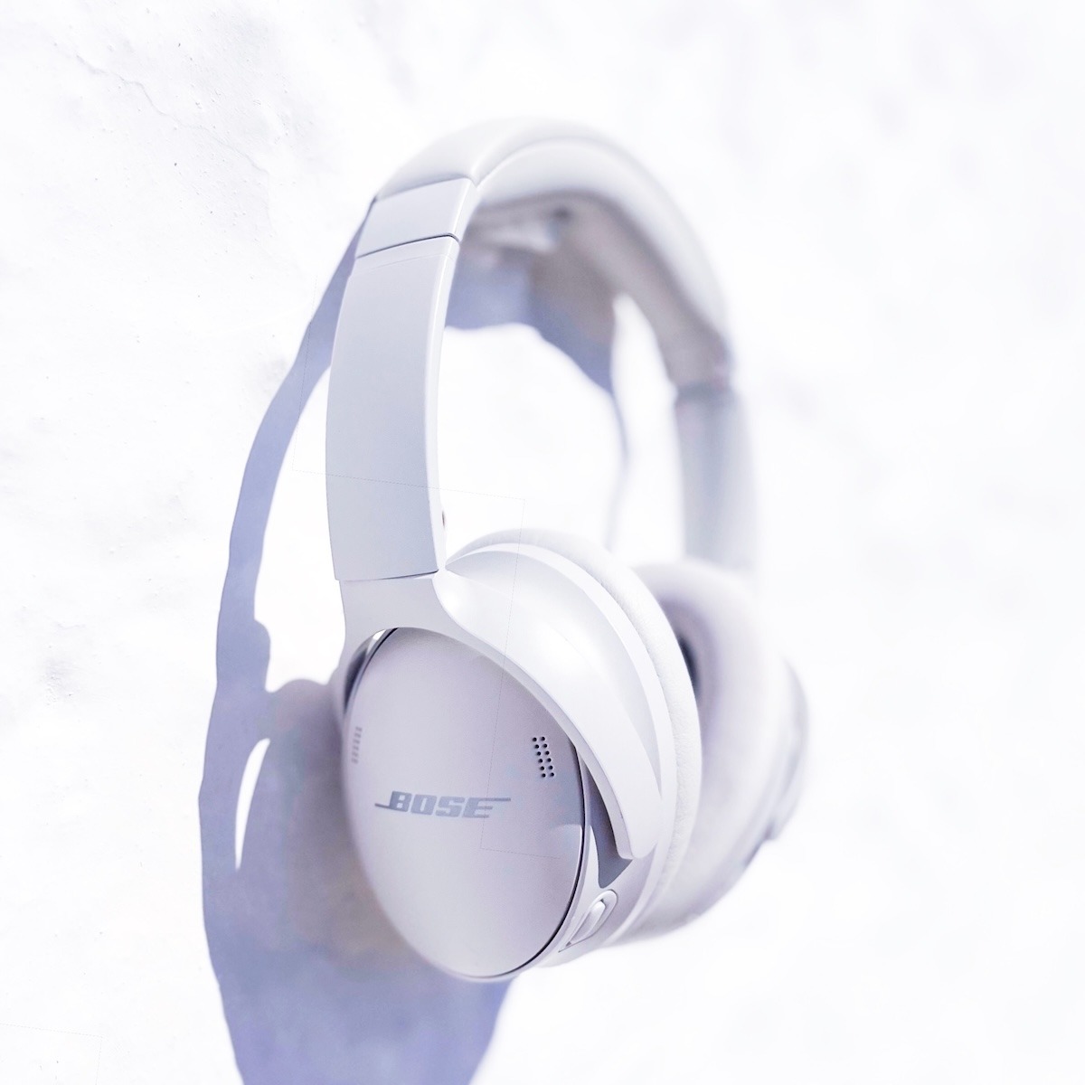 White headphones in front of a white washed stone wall to represent our Online Moon Sound Bath with planetary frequencies and Greek field recordings