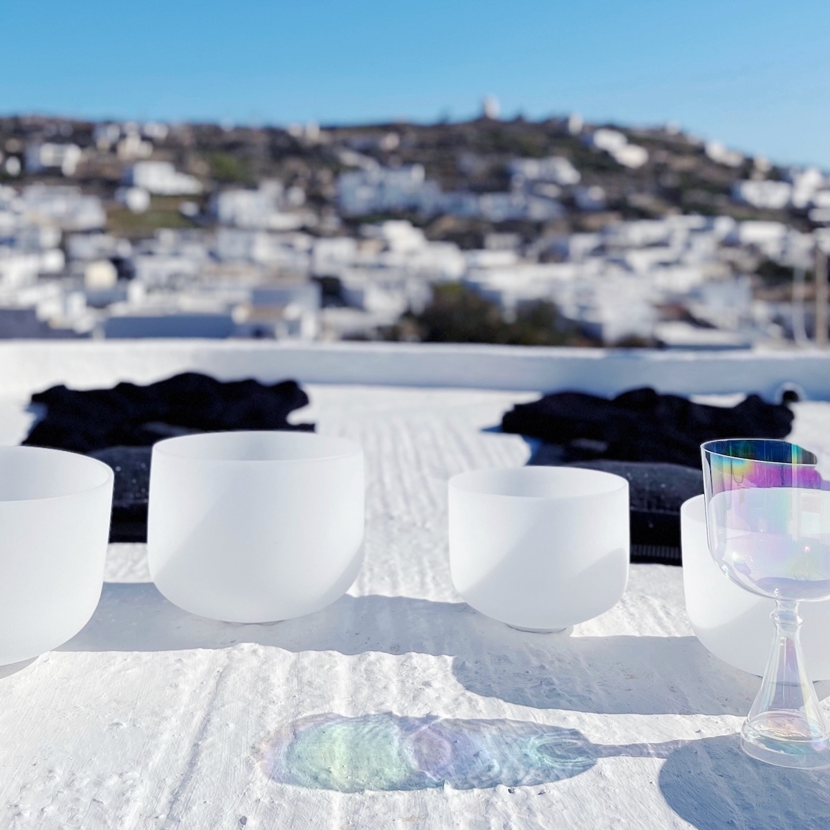 Sound Bath setup with crystal singing bowls on a white rooftop in Kimolos Greece