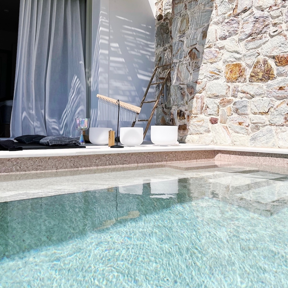 Private Sound Bath setup with crystal singing bowls beside a pool on Kimolos Island in Greece